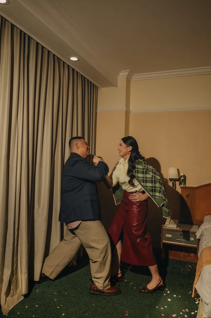 Rafli dan Dita berdansa di kamar hotel bercahaya hangat, Dita memakai selendang tartan