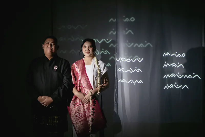 Rafli dan Dita di ruang gelap, aksara Lontara terproyeksi di tirai sebelah mereka